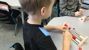 Curriculum - We are all Math People Young student sitting at a table, learning math