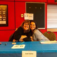 Two female staff sitting at a registration table smiling